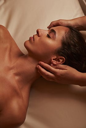 A woman with a relaxed expression getting a facial massage.