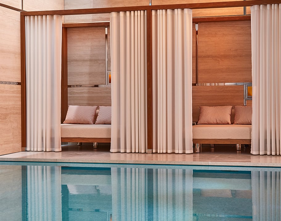 Wooden cabanas with cream drapes at the edge of the mineral pool