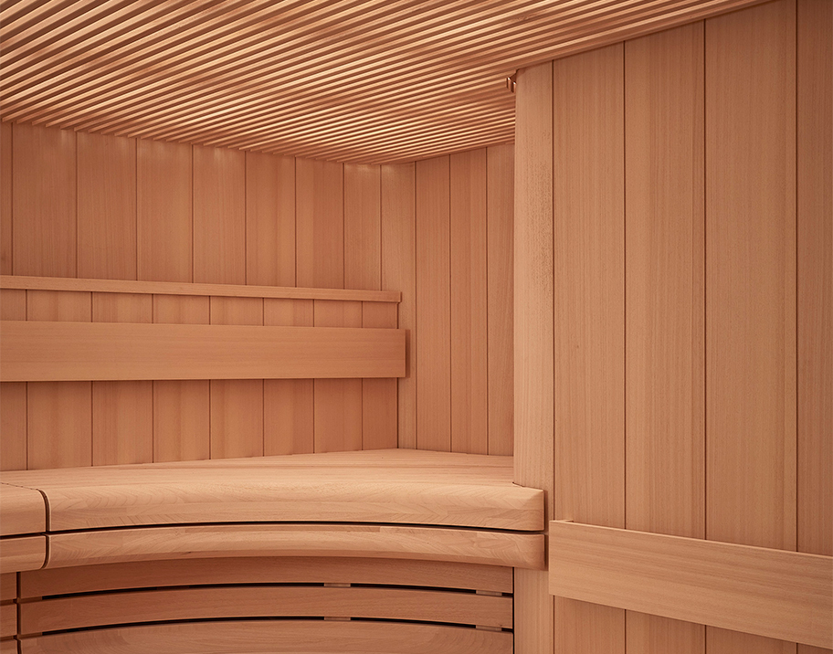 Curved pink hue wooden walls and panelled ceiling of the sauna